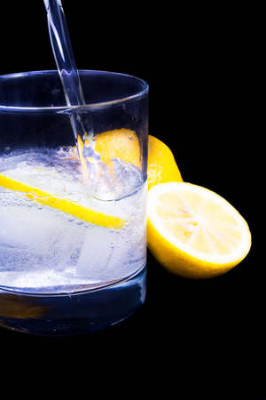 A refreshing drink being poured against black background