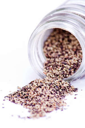 Fresh ground pepper spilling from glass containerの写真素材