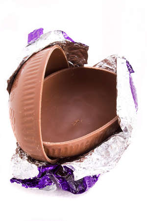 A halved milk chocolate Easter egg in foil wrappingの写真素材