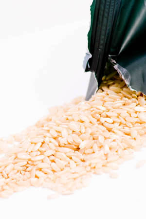 dried rice spilt from packaging over white