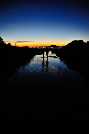 Romantic couple walking on a stream at sunset. の写真素材