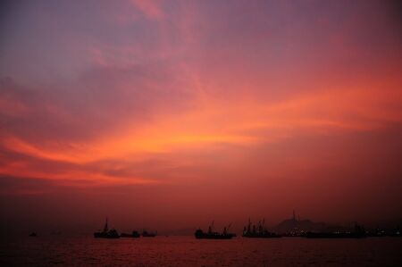 Burning Sky over the sea with some boat on the surfaceの写真素材