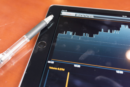 Tablet with stock graph on a wood tableの写真素材