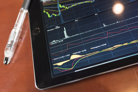 Tablet with stock graph on a wood tableの写真素材