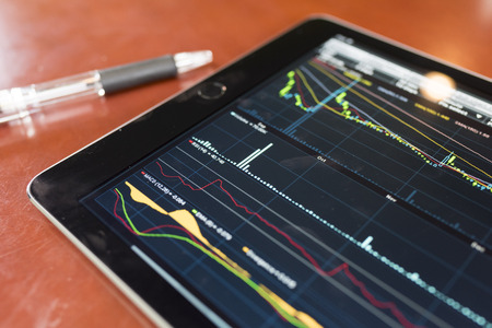Tablet with stock graph on a wood tableの写真素材