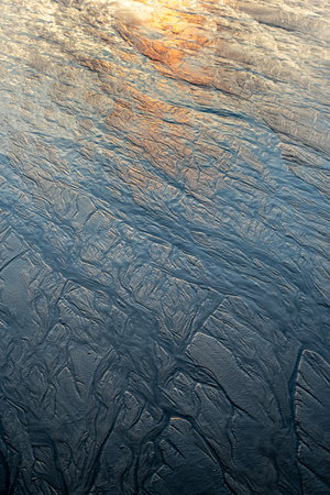 Magical morning seascape with rising Sun, water ripple and sand patterns, shallow, low tide.の写真素材