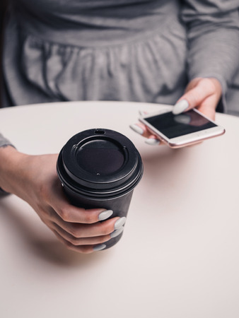 Coffee to go and smartphone in armsの写真素材