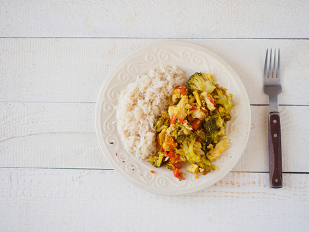 Chicken with rice and vegetables. White wood table.の写真素材