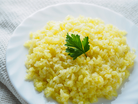 White plate with rice and green on table.の写真素材