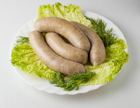 Raw sausages with greens on the plate.の写真素材