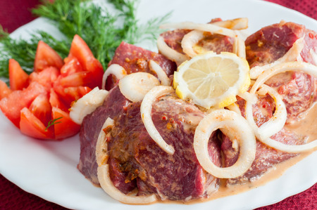 Raw pork beef meat with greens on the white plate.