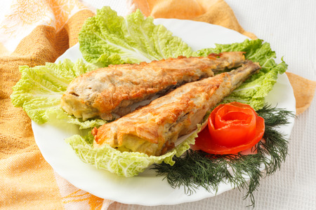 fish in batter with greens on a white plate.