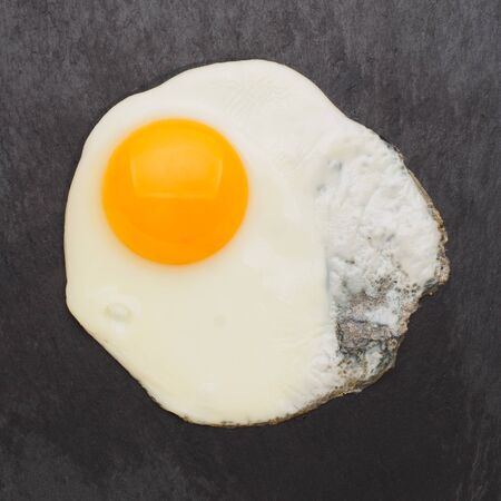 Fried egg isolated on black background top.