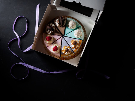 Set of pieces cakes in box on black background.の写真素材