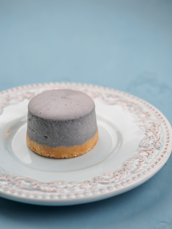 Small round blueberry cheesecakes on plate and blue background.