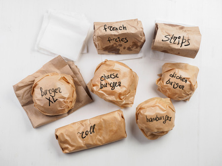 Burgers roll french fries strips on paper package with inscriptionの写真素材