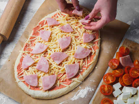cooking oval homemade pizza with ham cheese cherry. woman hands.の写真素材