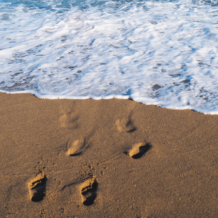 Sea ocean beach. Blue water with foam and footprints.の写真素材