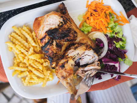 whole chicken with french fries and vegetables on the plate in cafe.の写真素材