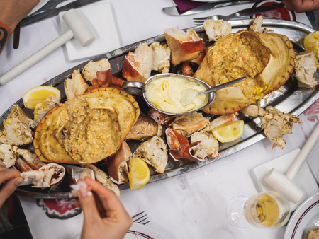 Plate of prepared boiled crabs in restaurant table. people hands.の写真素材