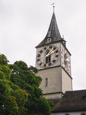 View of the tower of the Grossmunster cathedral with the clock tower of the Saint Peter Church in the foreground.の写真素材