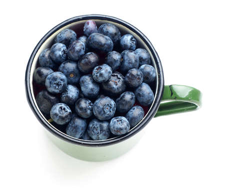 blueberries on green enamel  mug cup. isolated white background.の写真素材