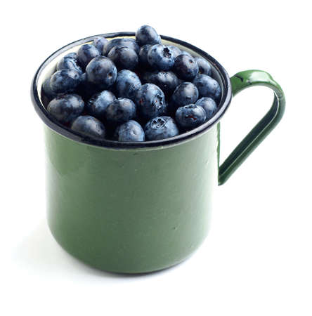 blueberries on green enamel  mug cup. isolated white background.の写真素材