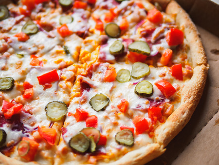 Cheeseburger pizza in delivery cardboard box on white table.の写真素材