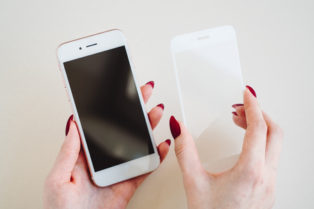 Smartphone with screen protect glass cover in hands. White background.の写真素材