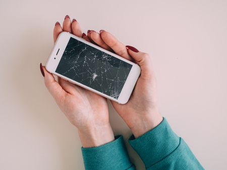 Broken glass screen smartphone in hand, white background.の写真素材