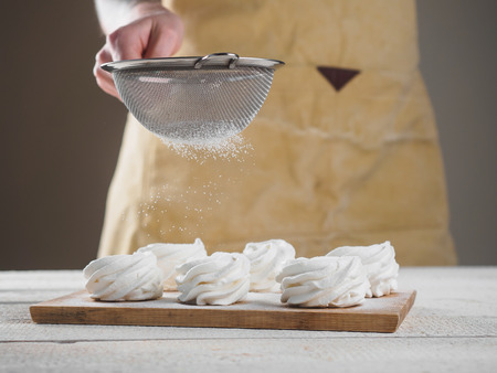 White homemade zephyr with sugar powder by woman hand.の写真素材
