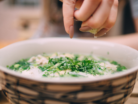 Vietnamese cuisine soup Pho Ga with chicken, noodles, fresh herbs and sauce in a bowl.