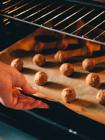Raw frozen meat balls on baking sheet with paper.の写真素材