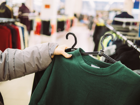 Young woman is browsing a rail of clothes at mall store.の写真素材