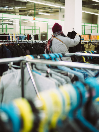 Young woman is browsing a rail of clothes at mall store.の写真素材