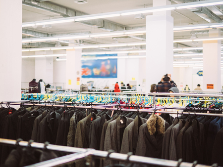 Young woman is browsing a rail of clothes at mall store.の写真素材