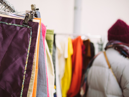 Young woman is browsing a rail of clothes at mall store.の写真素材