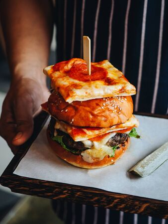 Big burger with beef cutlet, white bun and pepperoni pizza.の写真素材