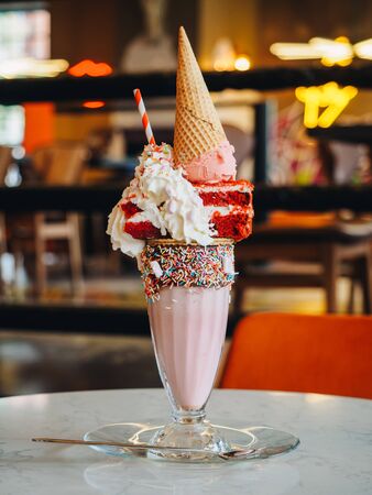 Pink freak shake with ice cream, cake and whipped cream.の写真素材