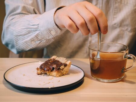 Man with beard and glasses in cafe eats dessert tea.の写真素材