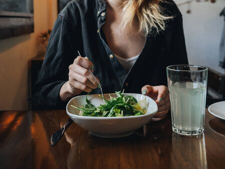 Girl woman eats salad in cosy cafe.の写真素材