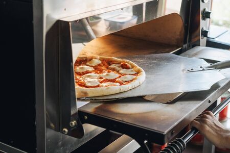 Cooking in modern pizza oven in cafe kitchen.の写真素材