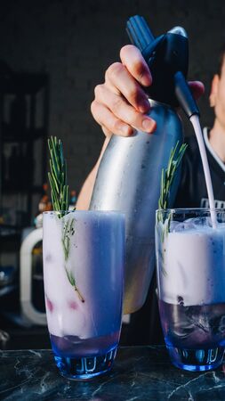 Bartender making alcohol cocktails with ice and rosemary at the bar.の写真素材