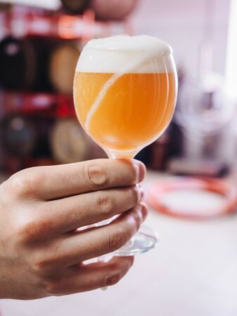 Glass of beer in male hand at the brewery factory.の写真素材