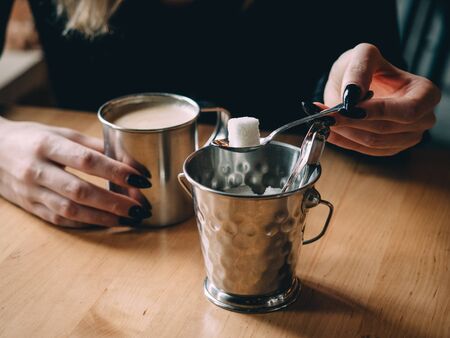 Coffee capuccicino enamel cup in female hands in cafe.の写真素材