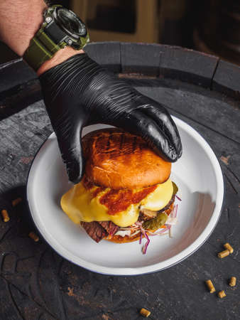 Burger with brisket meat, cheese, cole slow on black wooden barrel.の写真素材