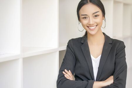Businesswoman cross one's arm,Professional woman is smiling in black suite.の写真素材