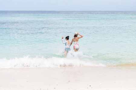 Beautiful young woman in bikini on the sunny tropical beach relaxing in waterの写真素材