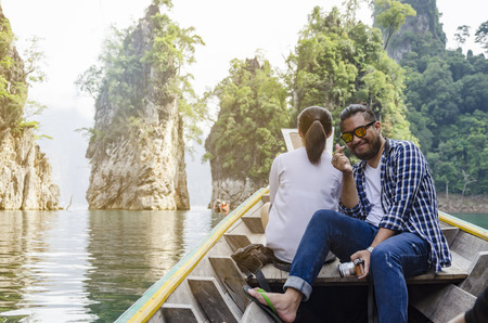 Man enjoying to adventure trip of a lifetime floating in a boat on the asia lake with sunset among the islands with mountainsの写真素材