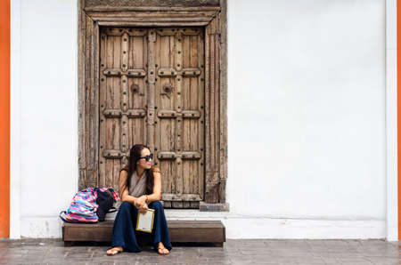 Travel guide. Young female traveler with backpack and with map on the street. Travel conceptの写真素材